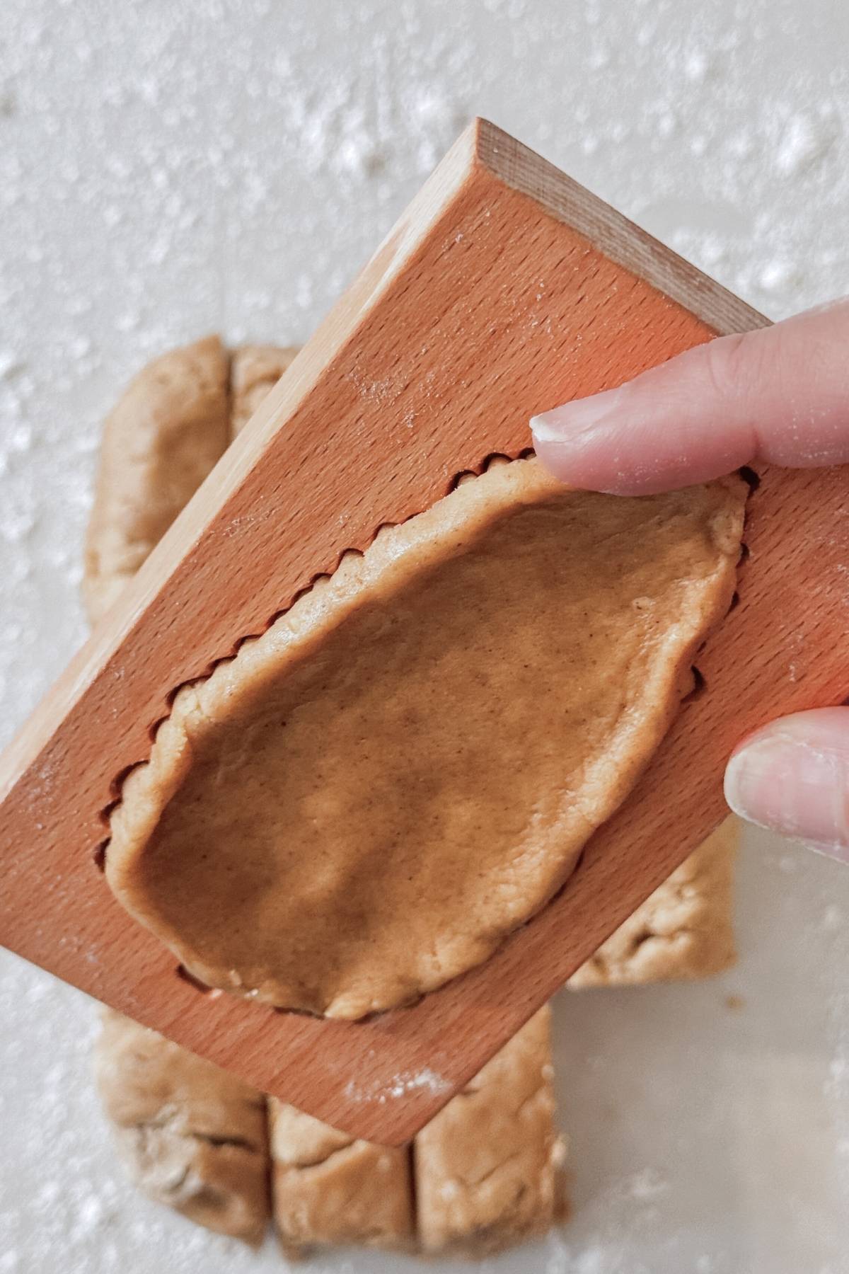 lifting gingerbread cookie dough from the wooden mold
