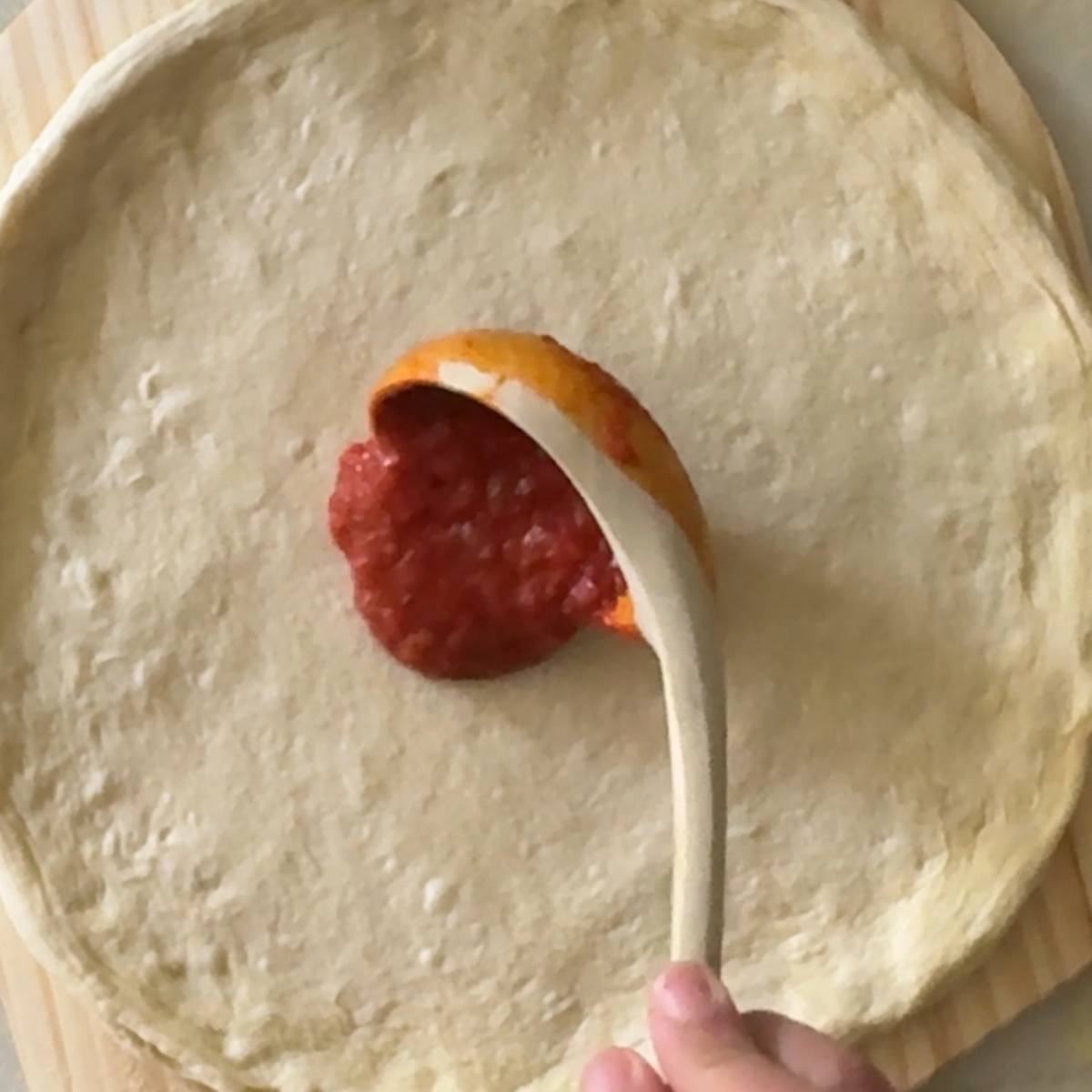 topping pizza dough with sauce