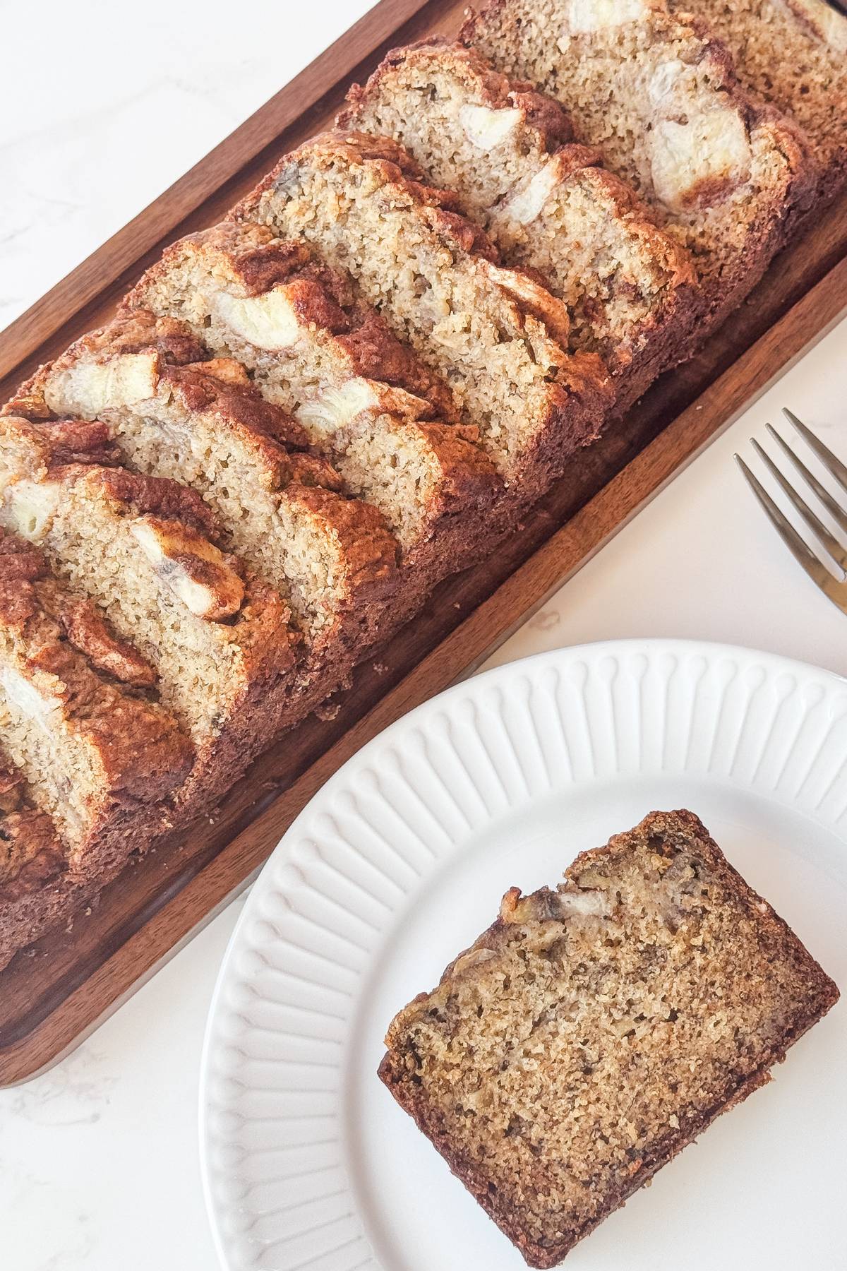 loaf of moist banana bread sliced and a slice is on a plate