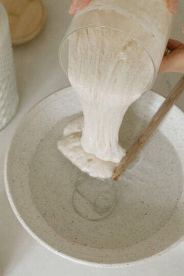 sourdough starter being poured on a bowl with water
