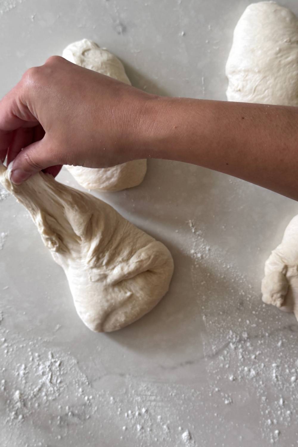 shaping sourdough pizza dough into balls by bringing all sides to the middle