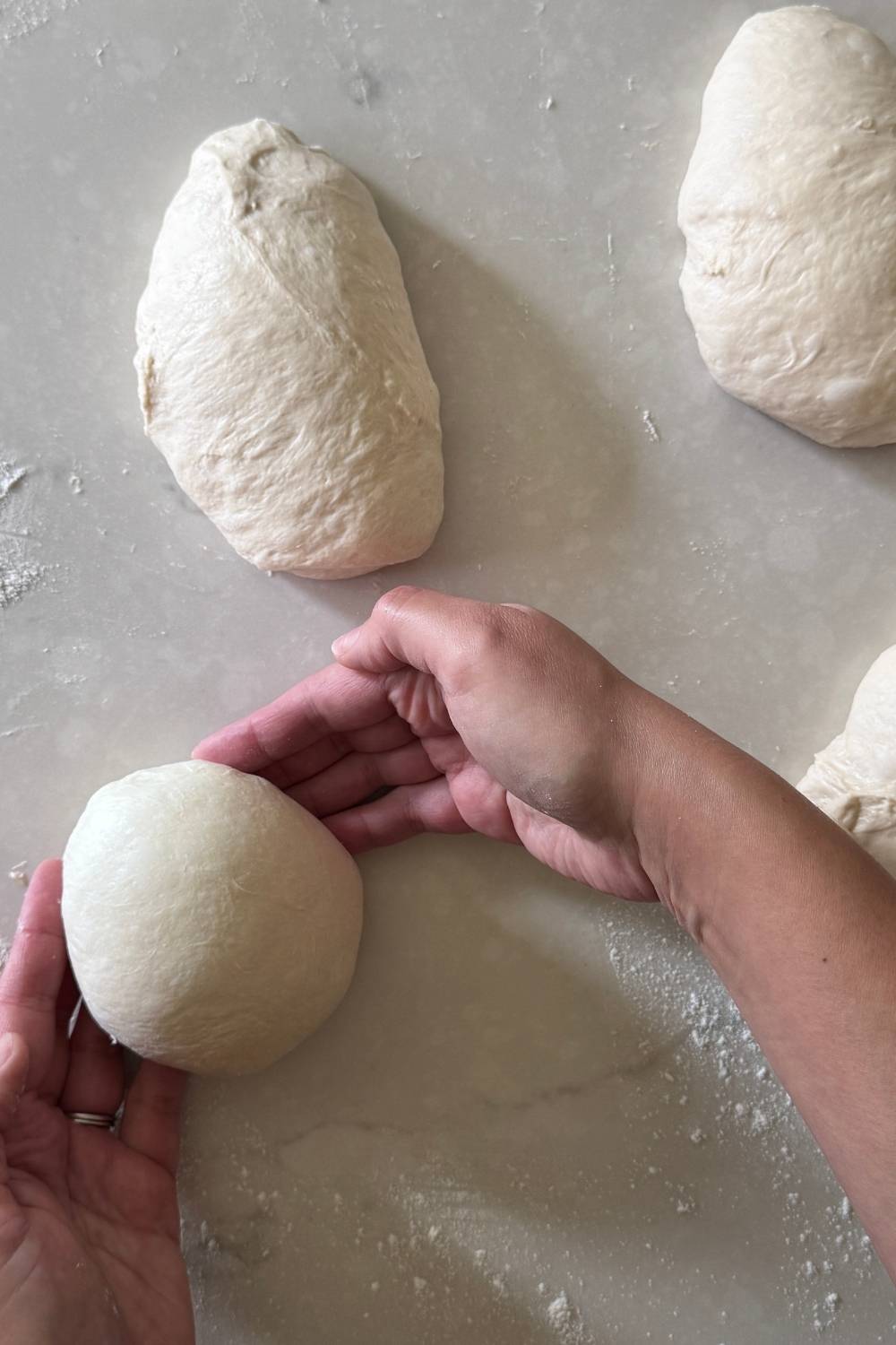 using hands to shape sourdough pizza dough into balls 
