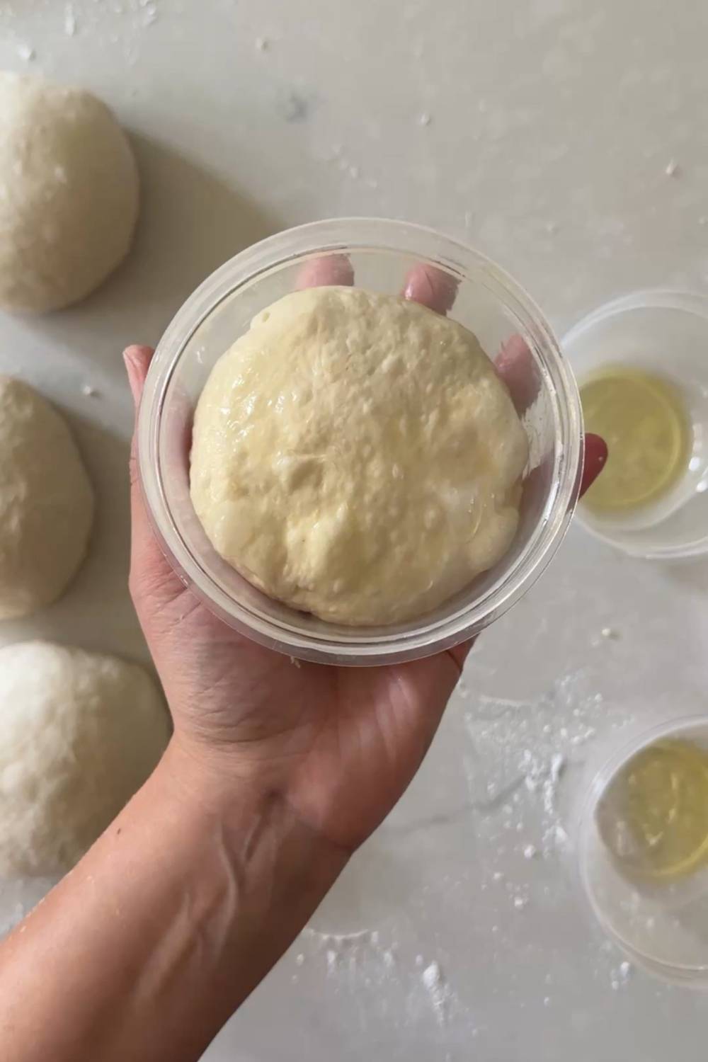 placing sourdough pizza dough ball in an oiled container