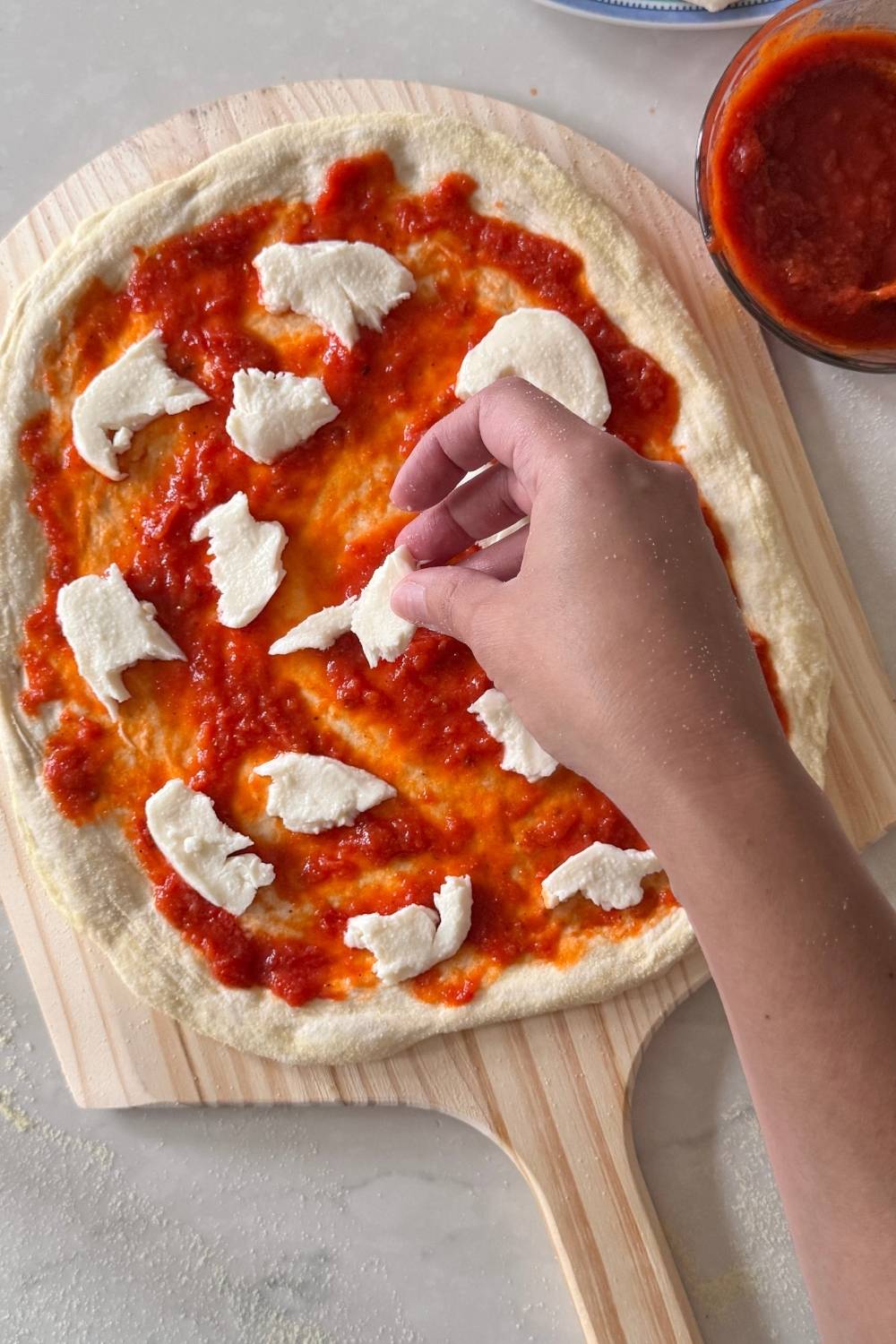 topping the sourdough pizza dough with cheese