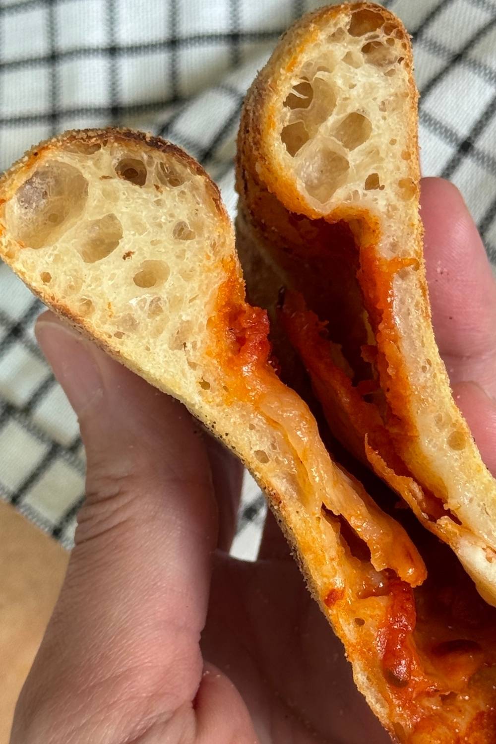 slice of sourdough pizza folded in half showing the airy crust