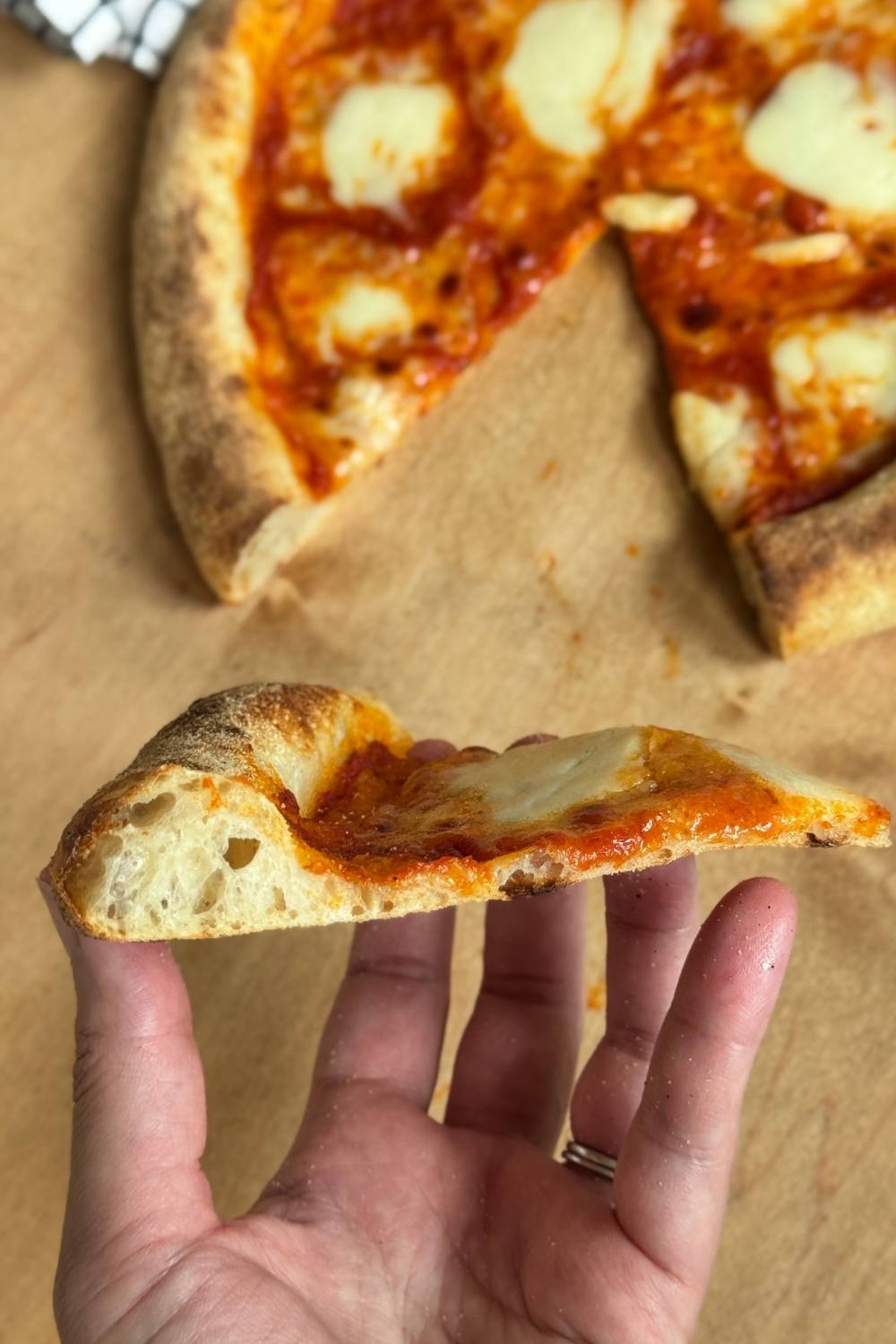 slice of sourdough pizza with big holes in crust