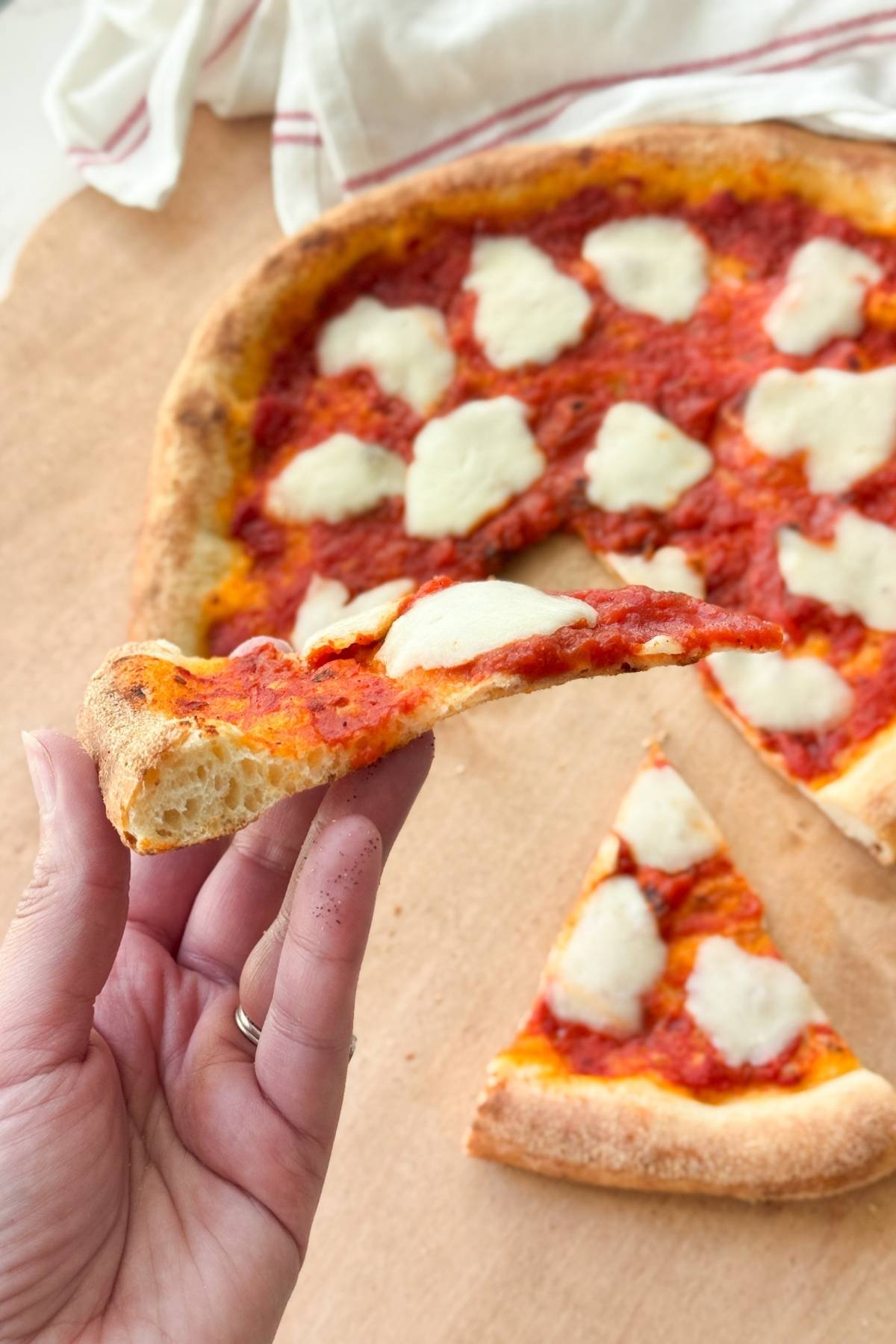 a slice of pizza with the rest of the pizza in the background