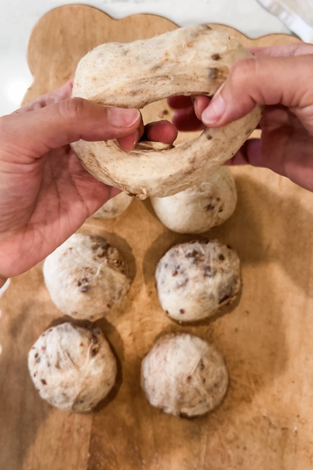 shaping Cinnamon Sugar Bagel balls into rings by poking and stretching a hole in the middle