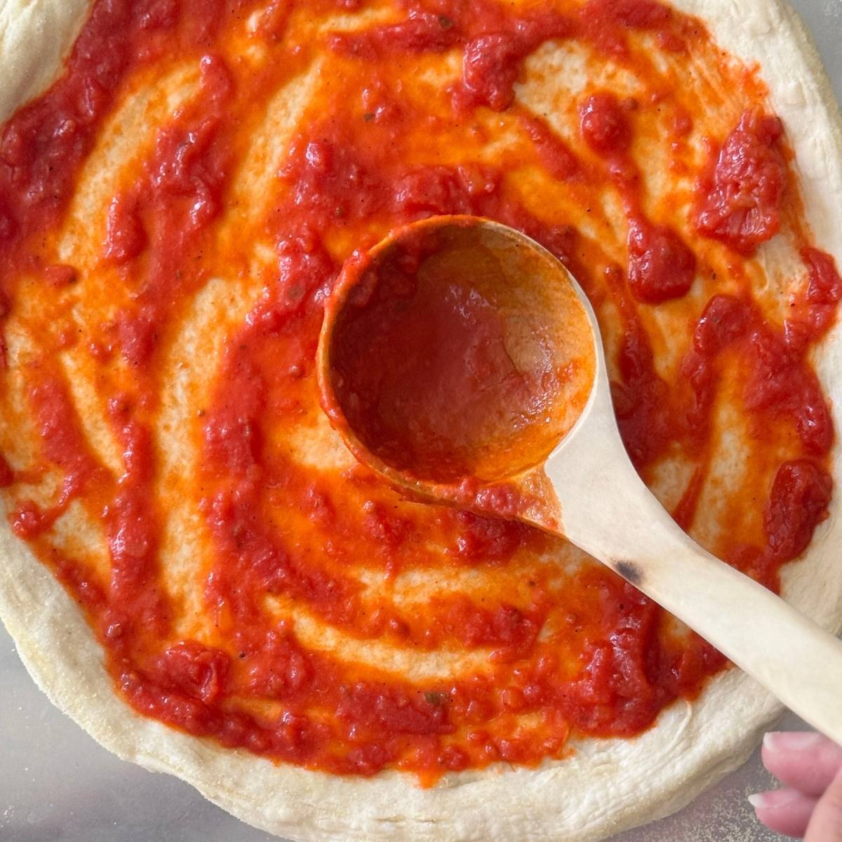 spreading sauce on top of the dough before baking