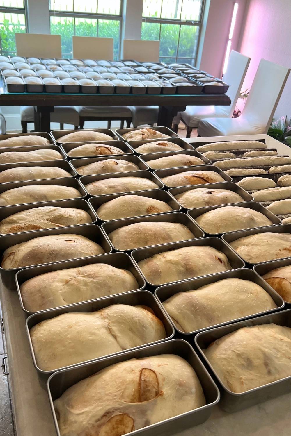 many loaf pans filled with dough sitting on a counter and table
