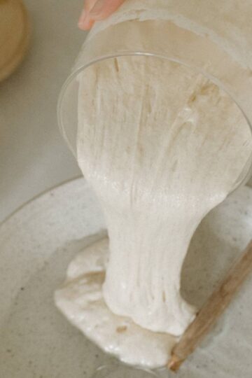 sourdough starter being poured on a bowl with water