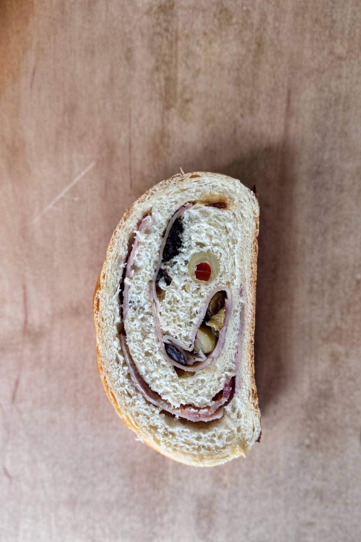 A slice of Sourdough Discard Pan de Jamon on a cutting board