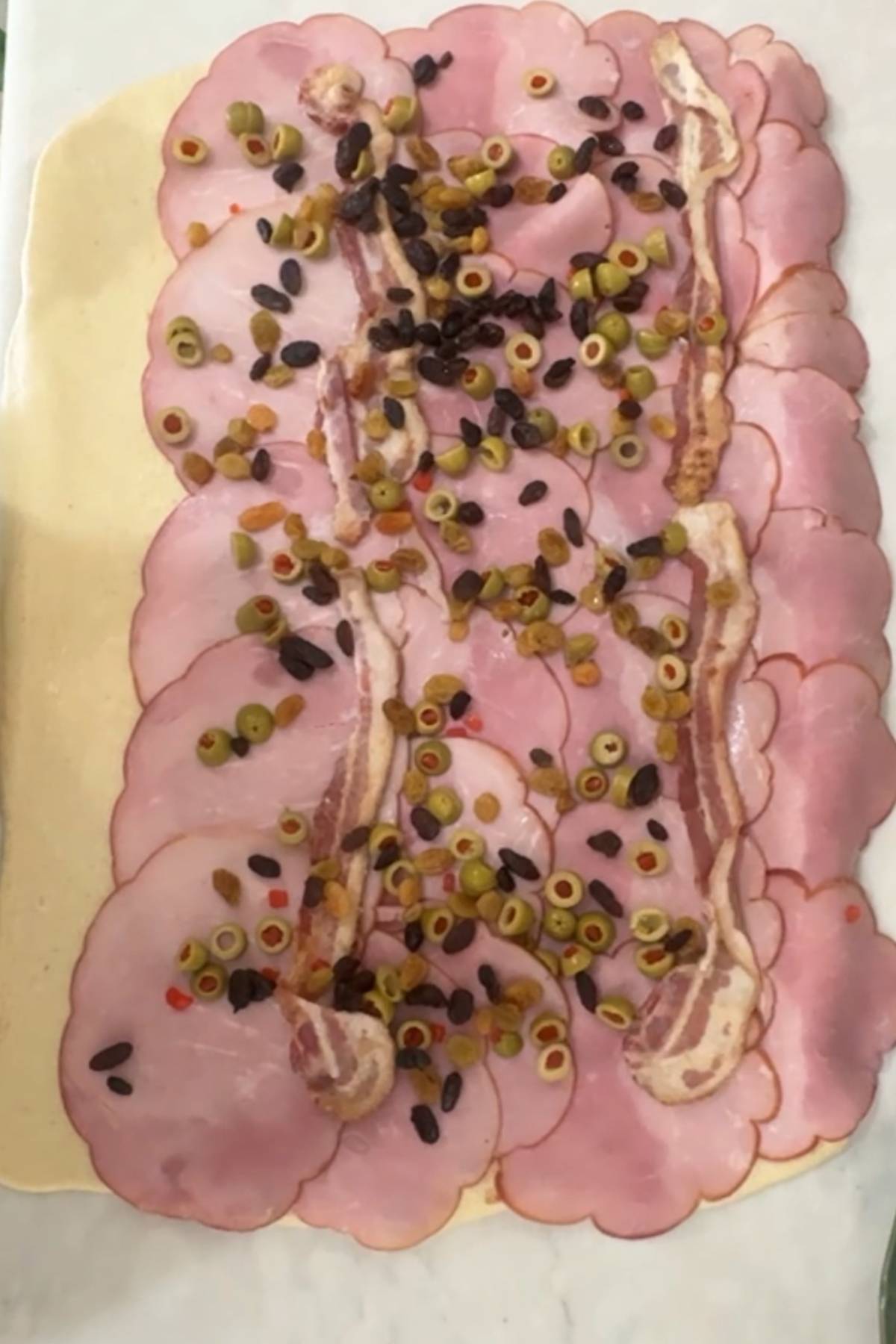 put the olives and raisins on top of the ham and bacon