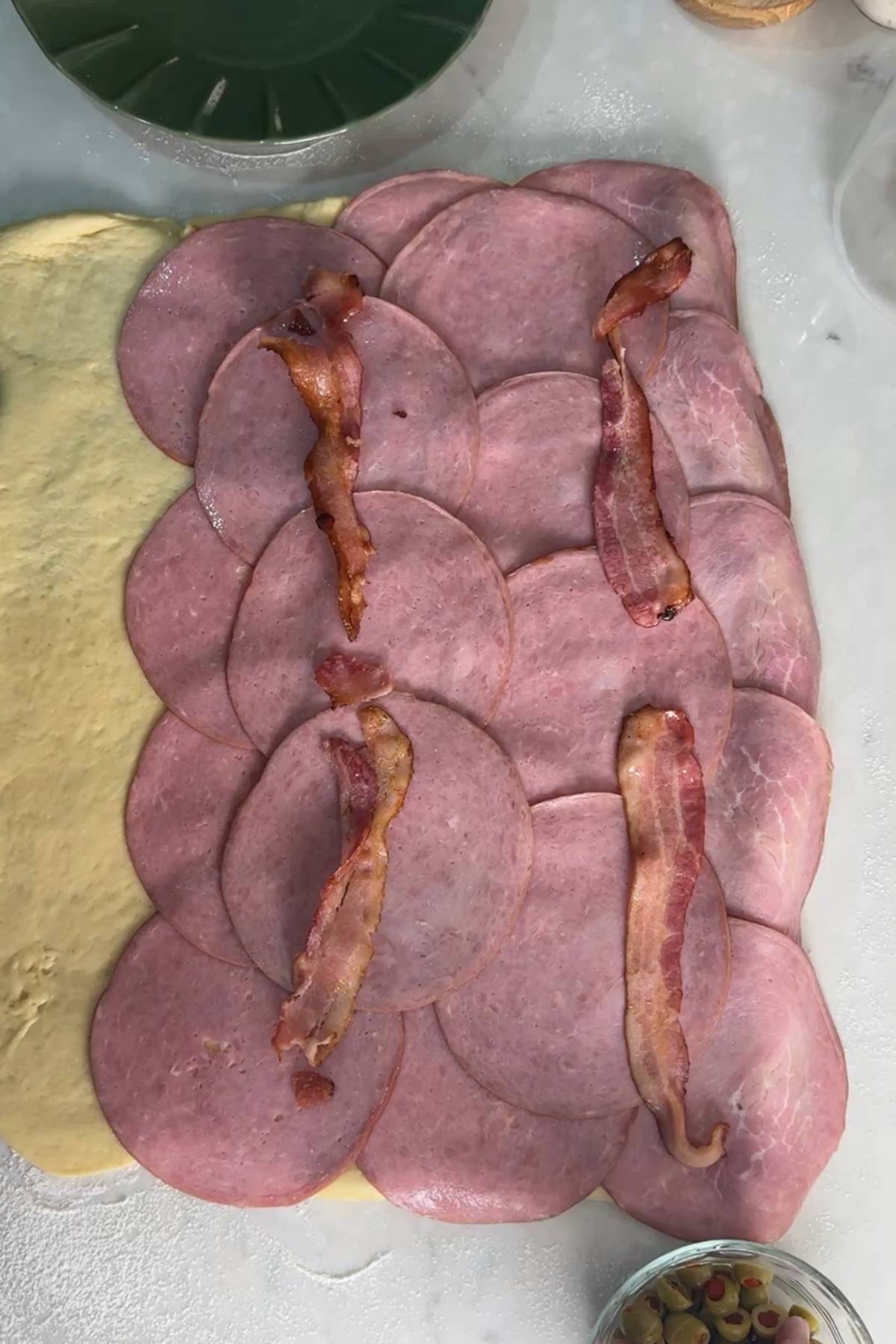 ham and bacon on top of rolled out Sourdough Pan de Jamon dough