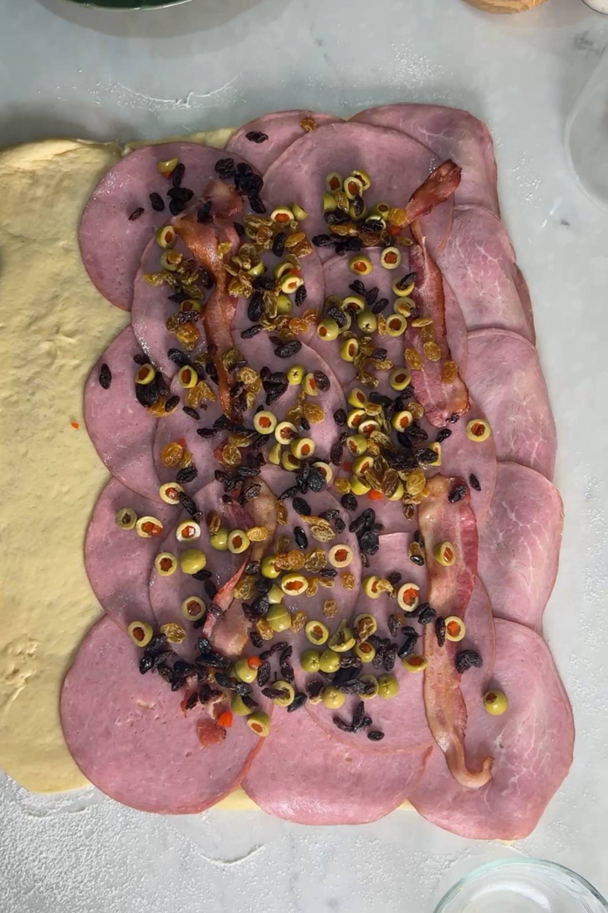 olives and raisins on top of the ham and bacon and rolled out Sourdough Pan de Jamon dough