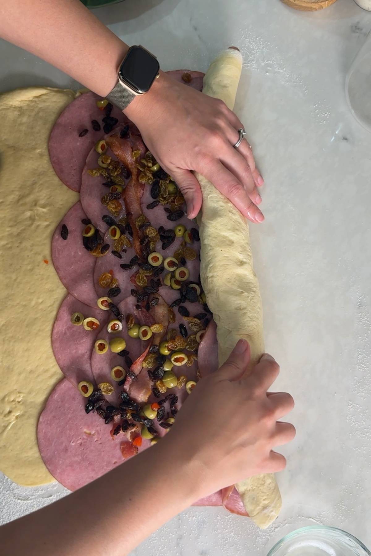 rollling the filled sourdough pan de jamon into a log
