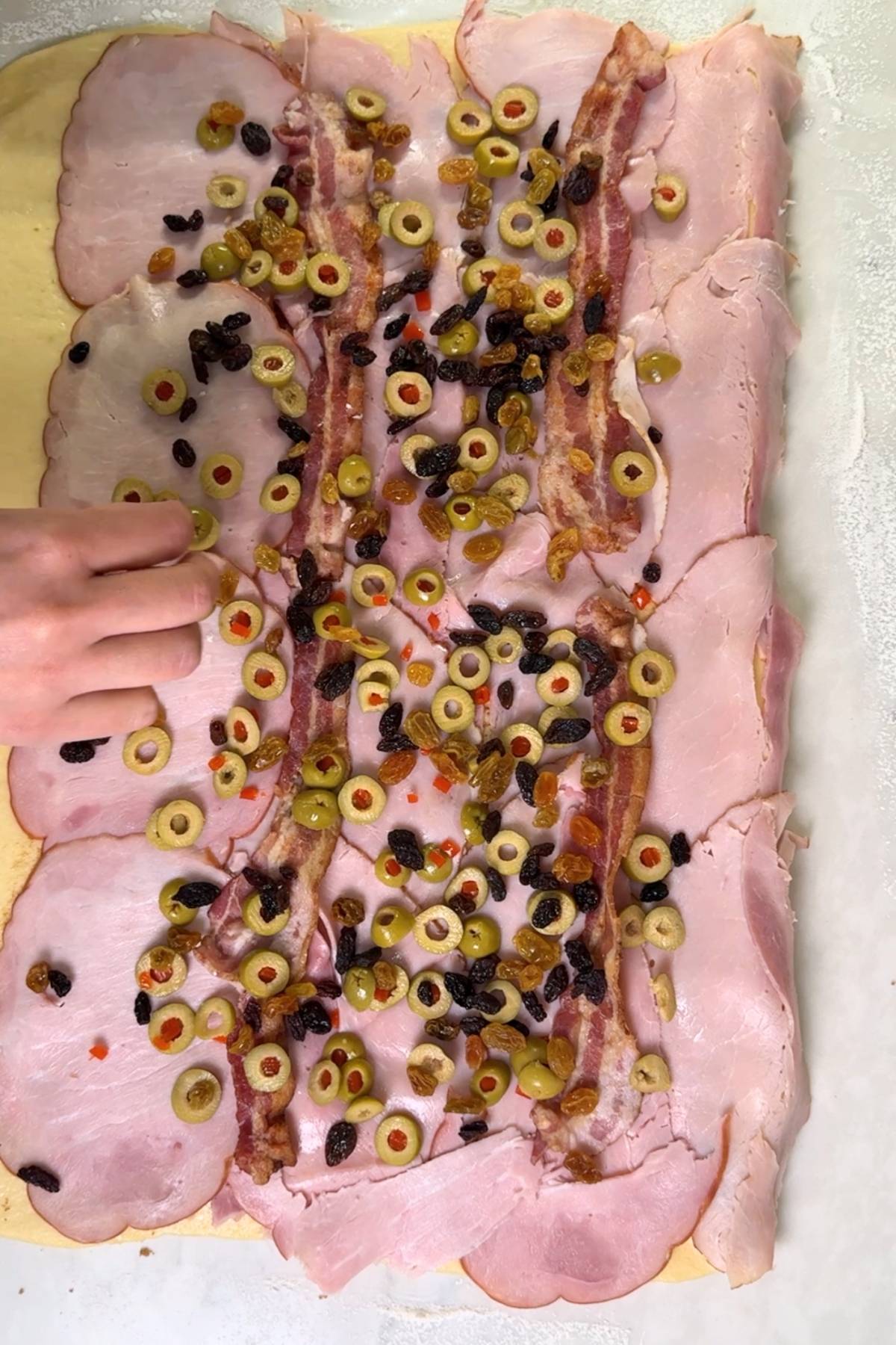 adding olives and raisins to the dough for Yeast Pan de Jamon